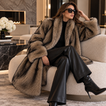 LuxeFur Kunstfell-Mantel in Camel mit breitem Reverskragen, sitzend auf einem cremefarbenen Sofa